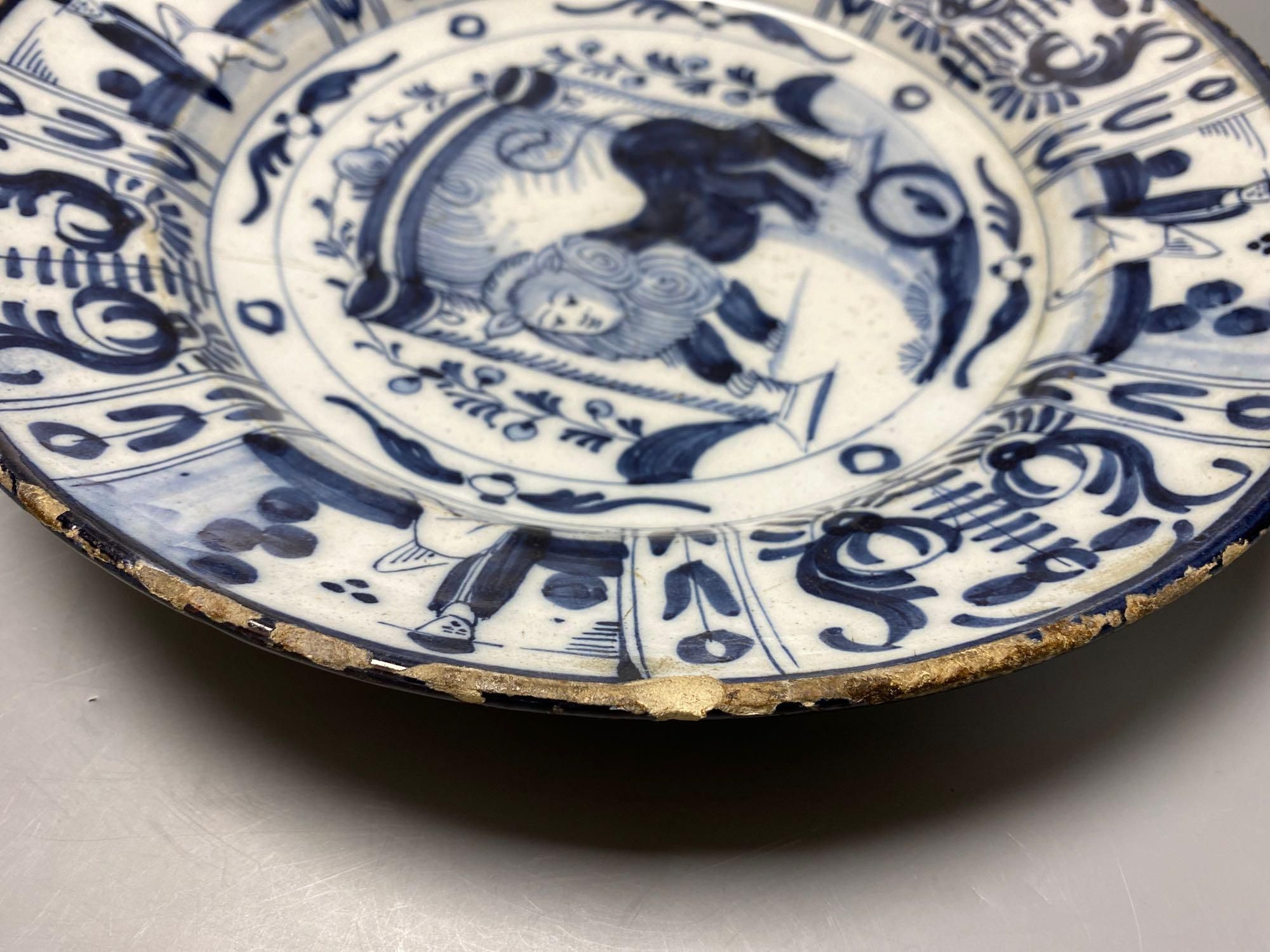 An 18th century Delft blue and white charger centred by a lion, with figural and foliate border, 32cm